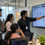 Students and trainer reviewing a DevOps task board at ScholarLogic, Bangalore